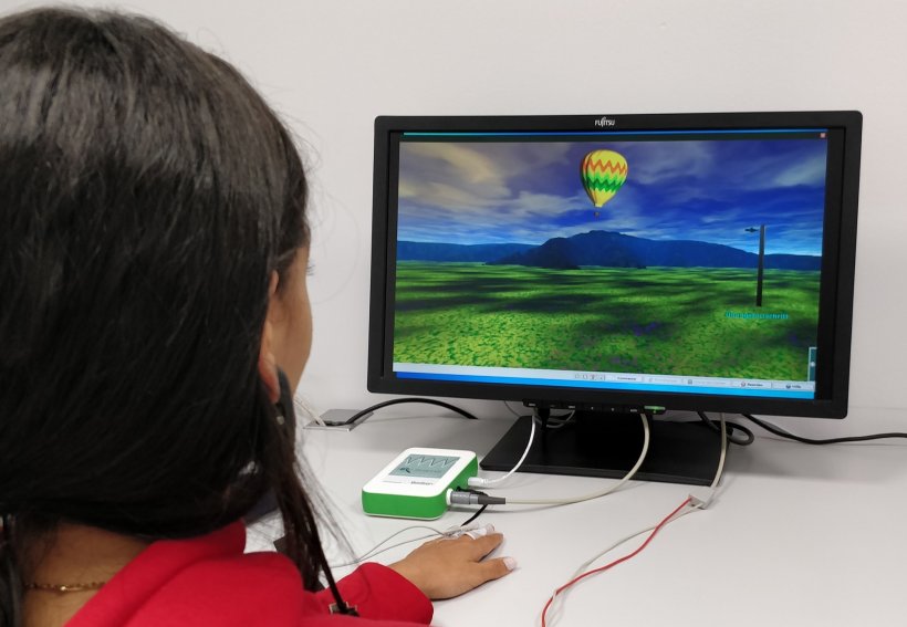 woman looking at computer monitor displaying virtual landscape with balloon