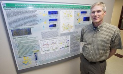 UM cell biologist Mark Grimes stands in front of a poster displaying the...