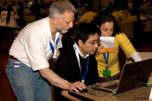 Two software engineers and an IHE-Europe monitor (yellow) solve a coding...