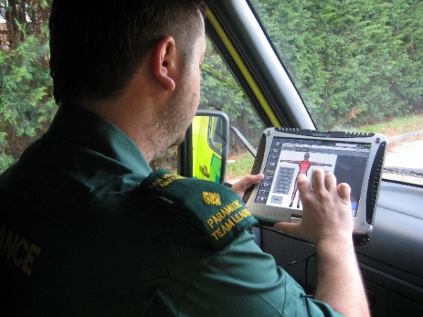 In an ambulance, a paramedic records data on the body mannequin graphic on...