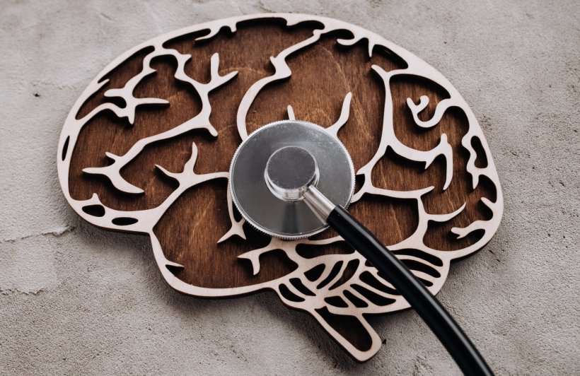 stethoscope lying on top of wooden shape of the human brain