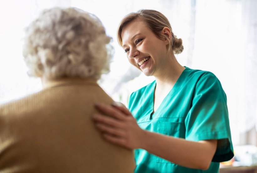 friendly nurse in green hospital garb tending to elderly patient