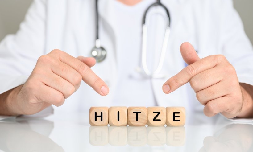 medical doctor pointing to word hitze (german for heat) spelled out in wooden...