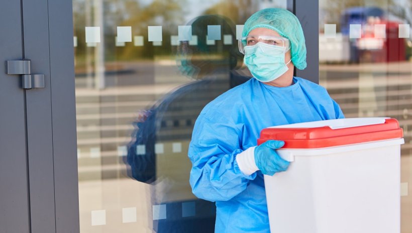 female surgeon carrying white box containing organ transplant