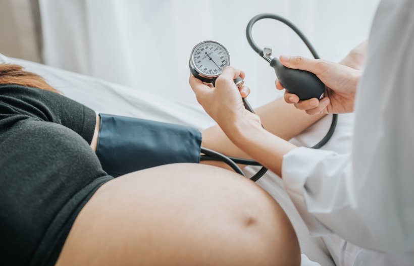 doctor measuing blood pressure with sphygomanometer on pregnant female patient