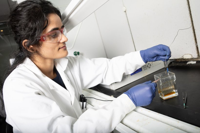Anuja Tripahi examining stainless steel sample in laboratory environment