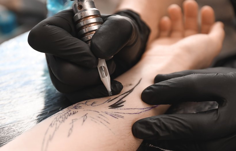 closeup of tattoo artist using needle to make tattoo on clients arm