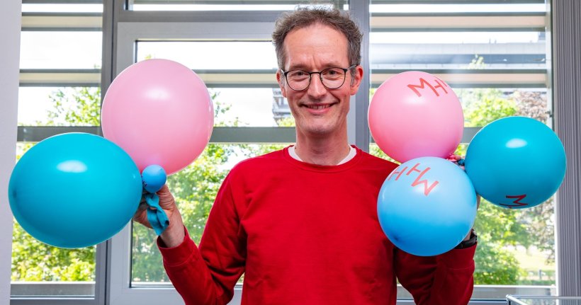 Professor Dr. Lars Knudsen hält blaue und rosafarbene Luftballons in den...