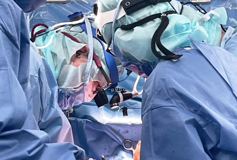 Two surgeons in an operating room, standing around the patient, looking down on...