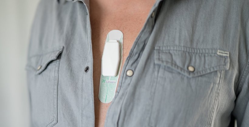 Closeup photo of a mans chest with unbuttoned shirt revealing a wearable sensor...