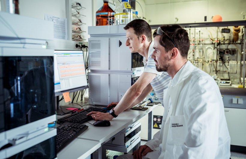 Two researchers in a laboratory environment, both looking at a computer screen