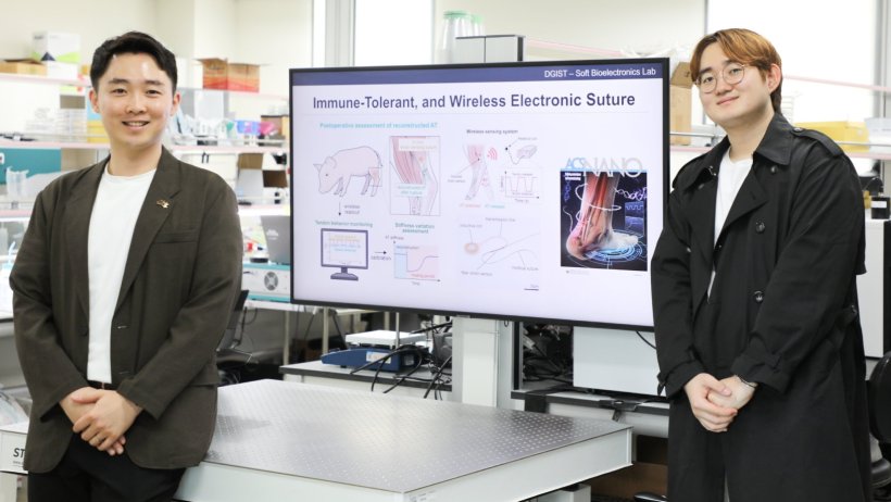 Two researchers standing to the left and right of a monitor displaying their...