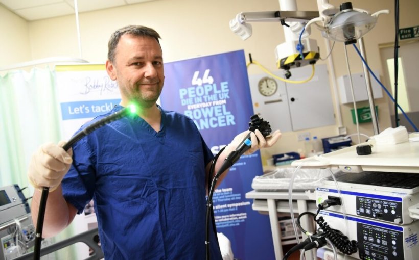 Professor Colin Rees holding a colonoscope with lit-up green tip