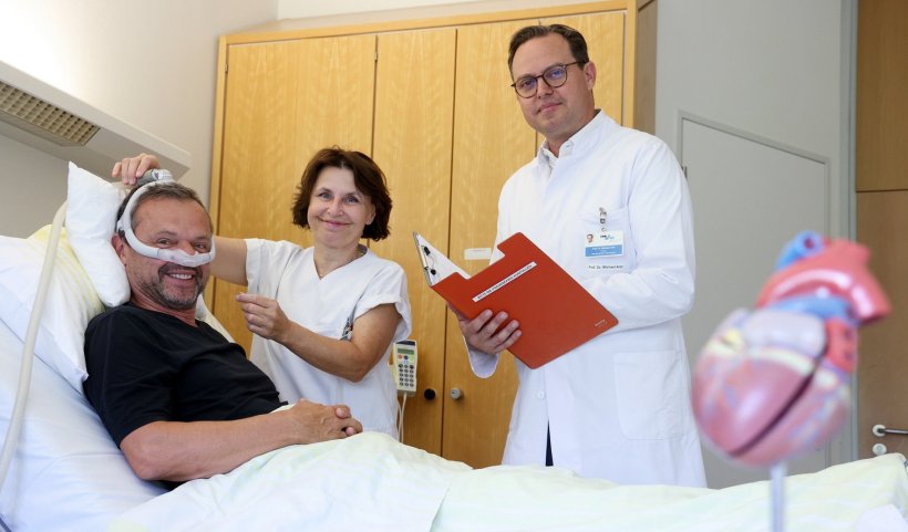 Ein Patient im Krankenhausbett trägt eine Atemmaske über die Nase. Neben dem...