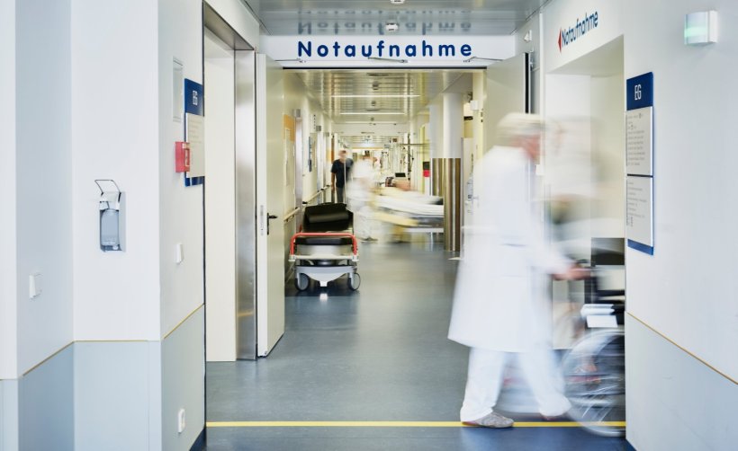 Ein Krankenhausflur mit einem Notaufnahme-Schild. Ein Arzt schiebt einen...