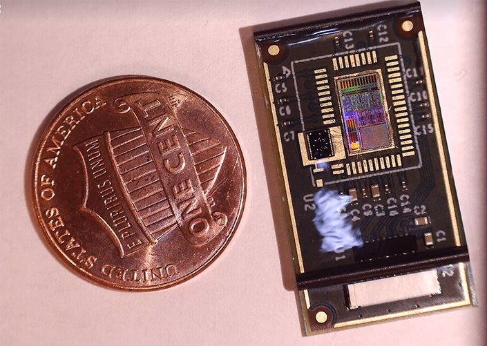 A microchip next to a one-cent coin for size comparison