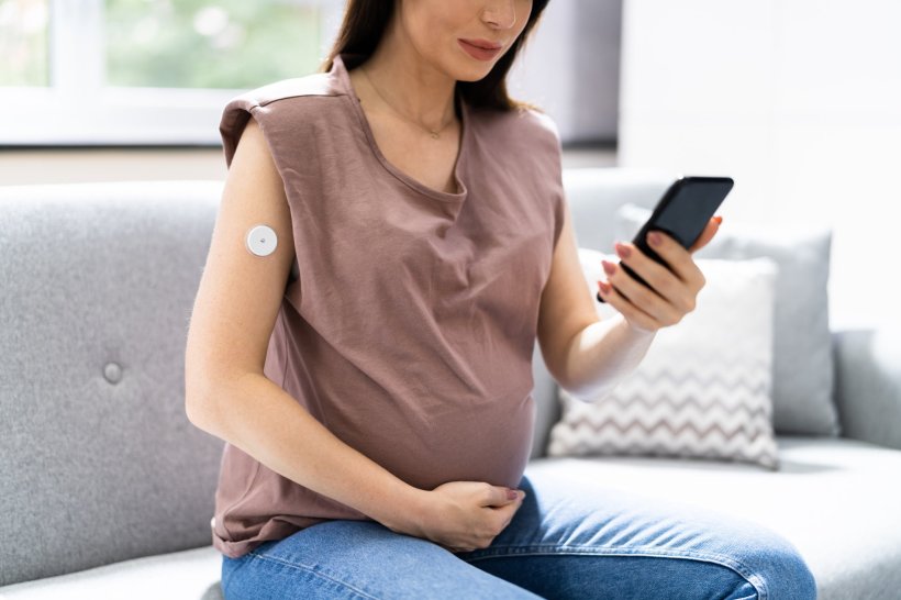 A pregnant woman is looking at her smartphone to see the values of her...