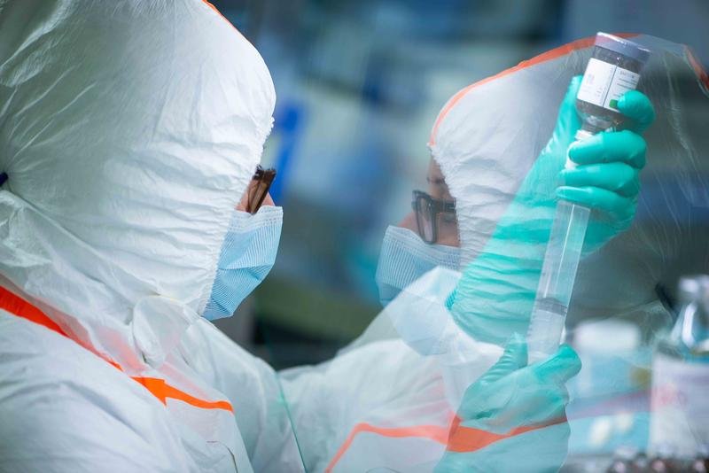 A lab worker is inspecting a vial.