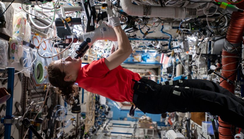 A female astronaut floating in the International Space Station, operating a...