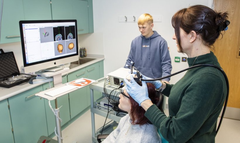 A female patient is treated with transcranial ultrasound by two researchers....