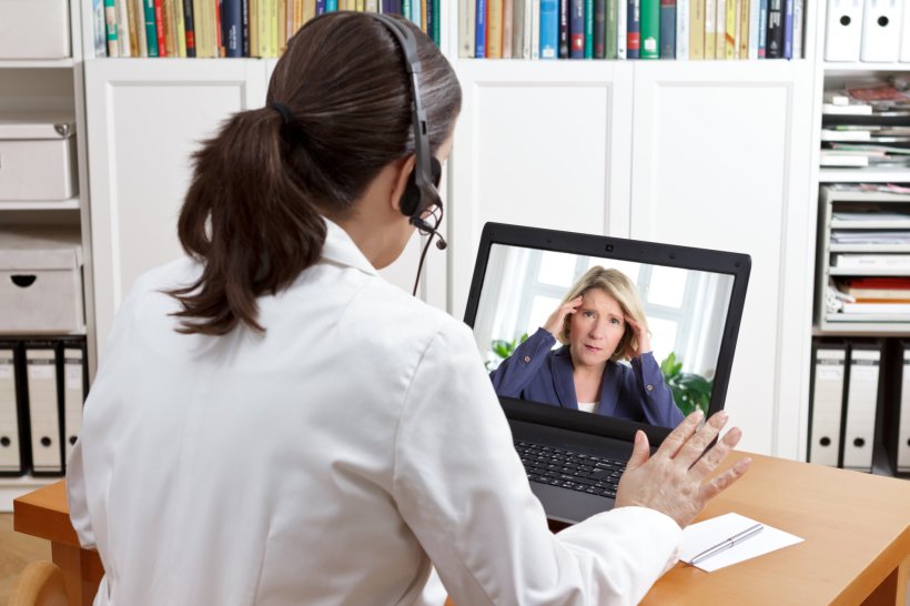 Female doctor wearing headset in front of her laptop computer, in remote...