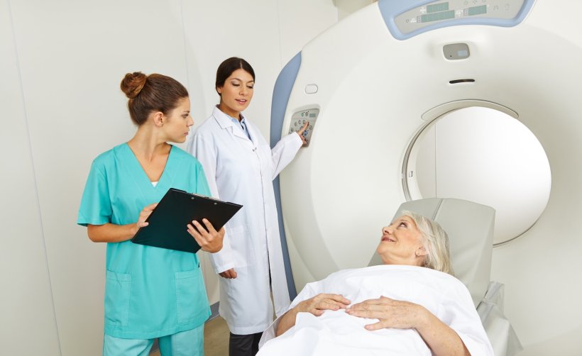 Zwei Medizinerinnen untersuchen eine ältere Patientin mit einem CT-Scanner