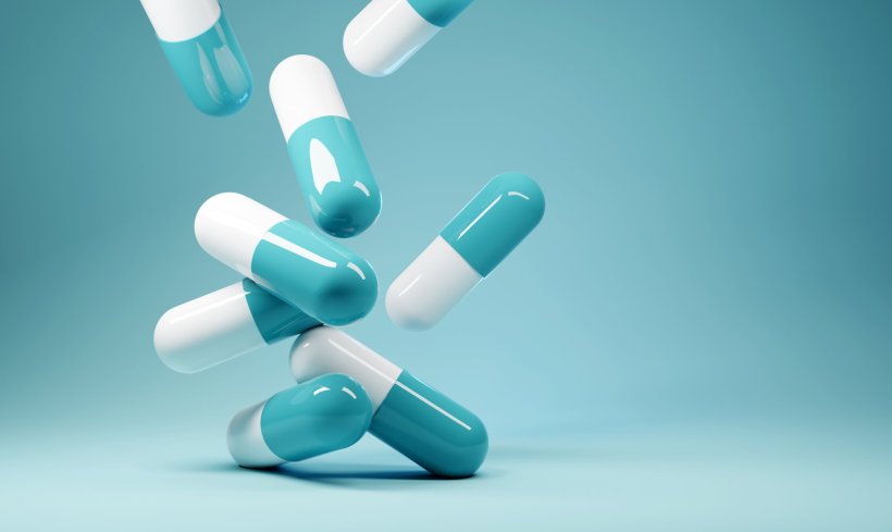 Several 3D rendered pills in turquoise and white falling down