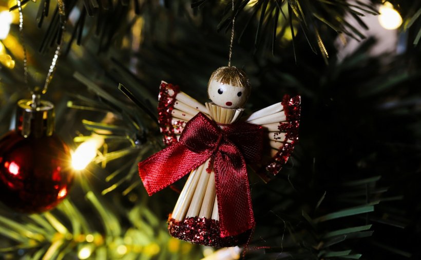 Christmas decoration straw angel hanging in a Christmas tree with baubles and...