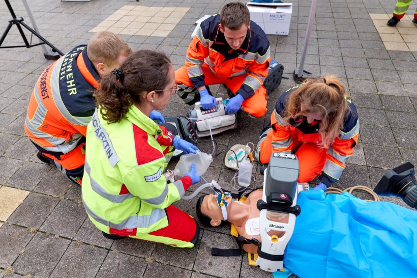 Mehrere Rettungskräfte knien um eine menschliche Simulationspuppe zur Übung...