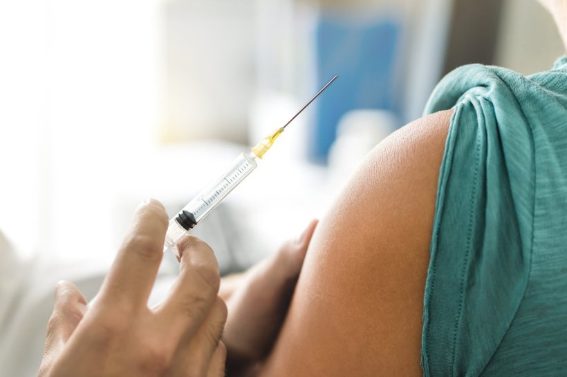 A doctor administers a vaccine into a patients arm with a small syringe