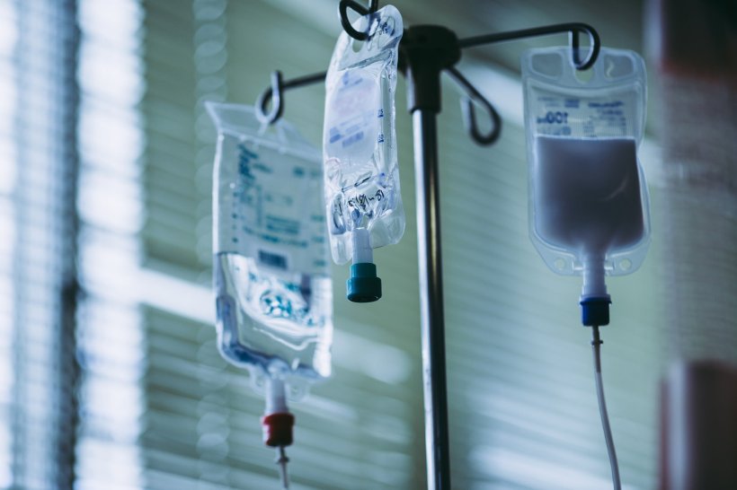 Three IV bags hanging from a holder in a hospital