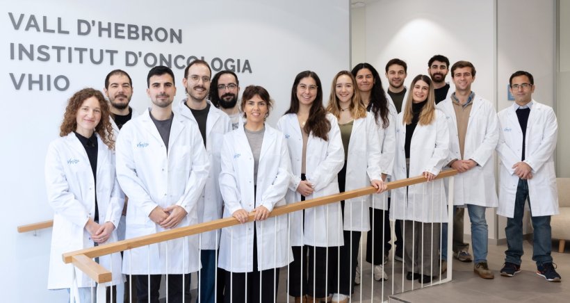 Group photo of 14 people in white lab coats