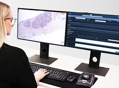 A woman is sitting in front of a computer setup with keyboard, mouse, and two...