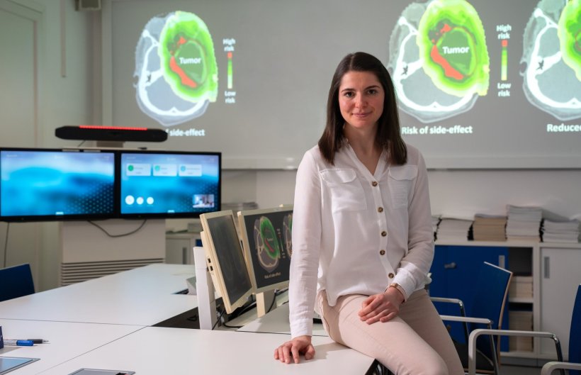 Martina Palkowitsch sitzt auf einem Tisch, auf dem mehrere Computermonitore mit...