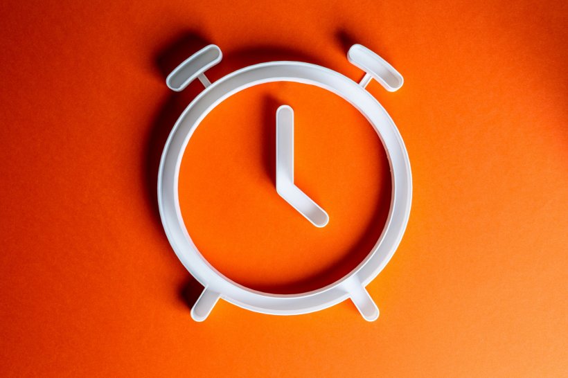Weißer Umriss eines Weckers auf orangefarbenem Hintergrund