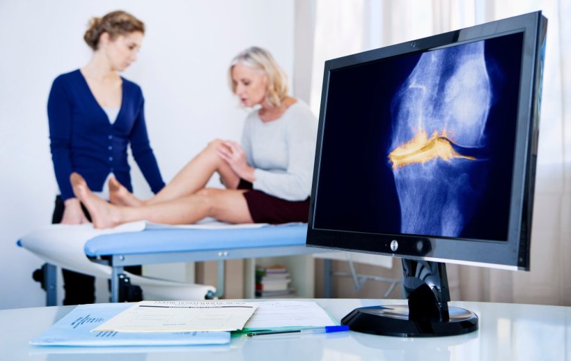 A computer monitor is displaying an xray of a knee, with yellow marks...