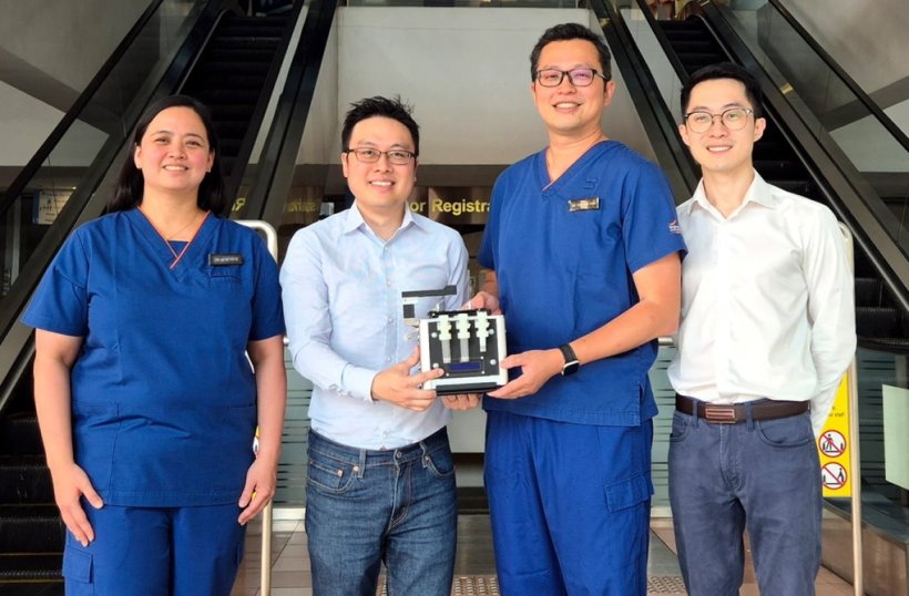 Group photo of four research team members in front of a hospital entrance...