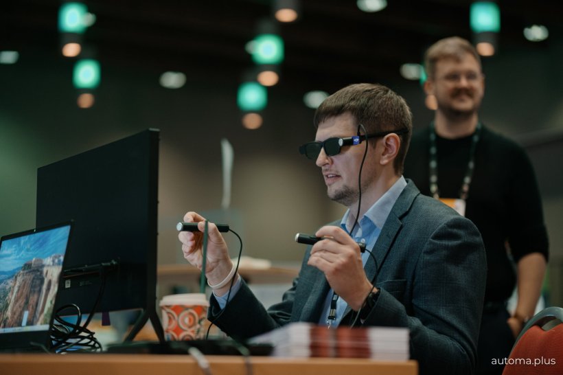 A man wearing digital glasses sitting at a table in front of a computer...