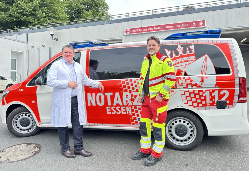 Prof. Dr. Marcel Dudda und Dr. Bastian Brune stehen vor einem Notarztfahrzeug,...