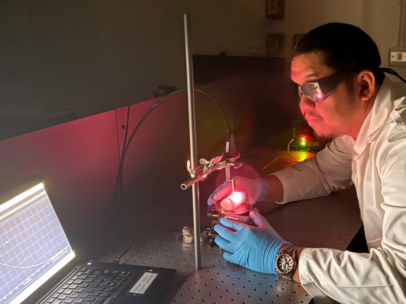 A researcher wearing specialized safety glasses looking at a glowing red object...