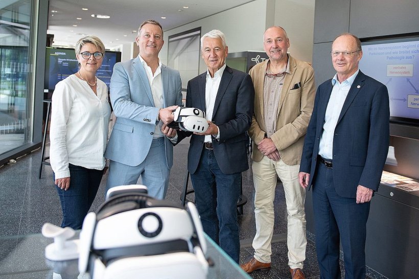 Fünf Personen stehen für ein Gruppenfoto nebeneinander. Zwei von ihnen halten...