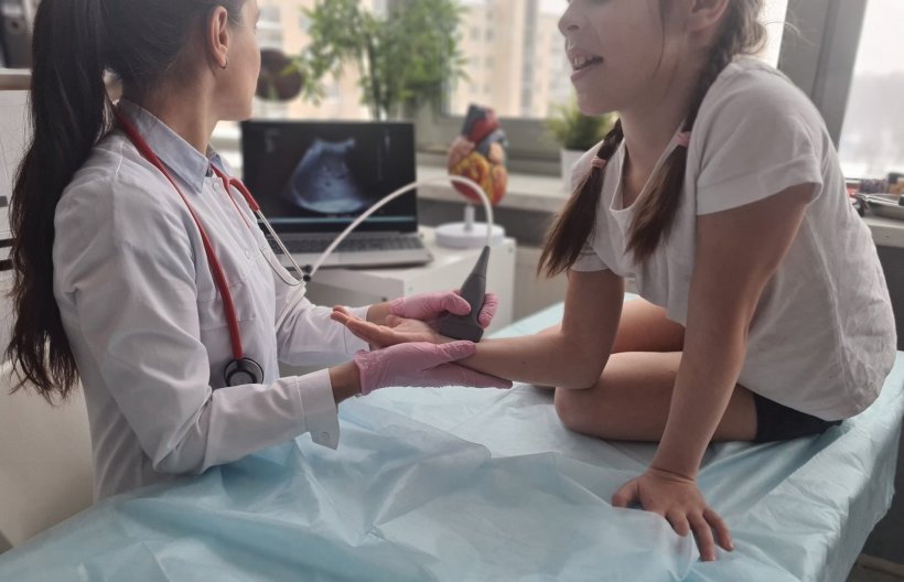 Eine Ärztin untersucht das Handgelenk eines Mädchens per Ultraschall