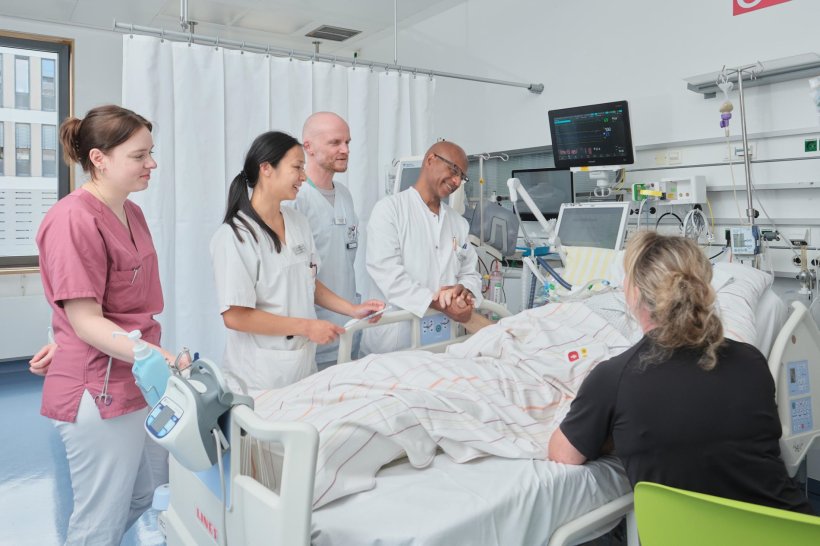Ein Team von Medizinern steht versammelt um das Bett eines Patienten auf der...