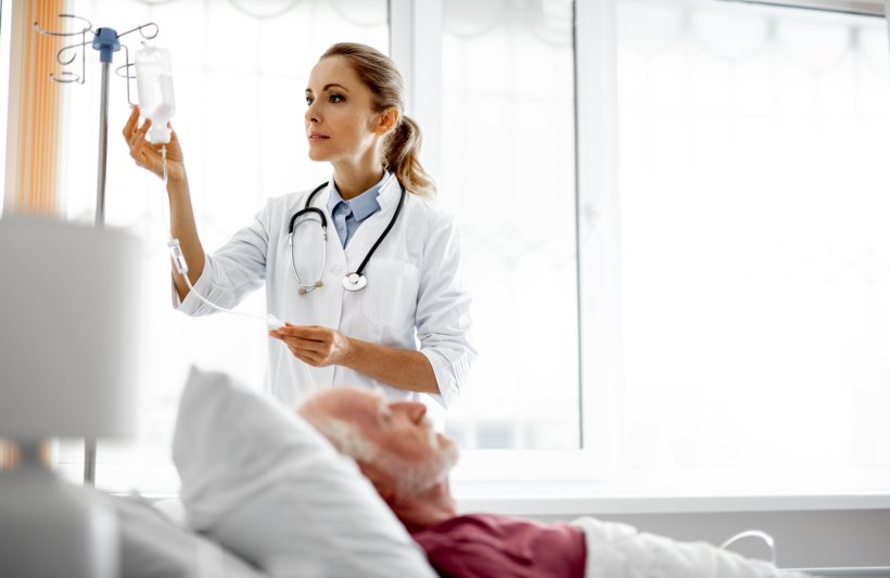 A female doctor with a ponytail wearing a white coat and a stethoscope around...