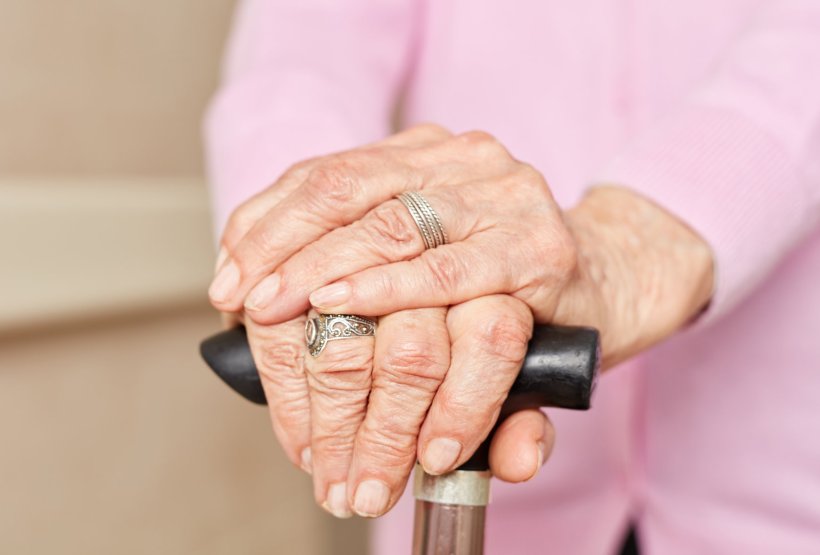 Closeup photo of the hands of a senior woman grasping her walking cane