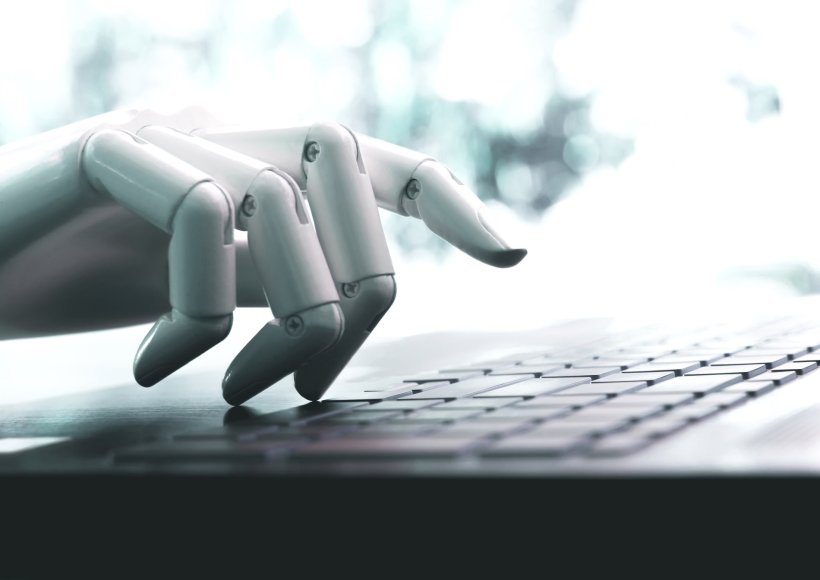 A robotic hand is hovering above a computer keyboard, symbolic image for an...