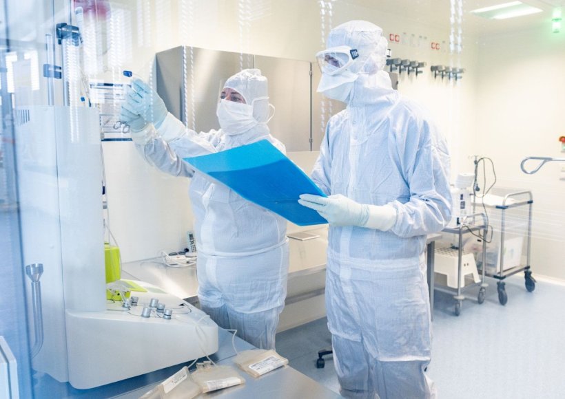 Zwei Wissenschaftler in Ganzkörper-Schutzanzügen bedienen im Reinraum einer...