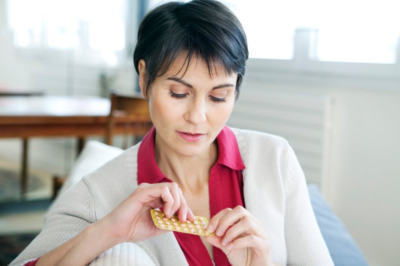 A woman is extracting a pill from its blister packaging