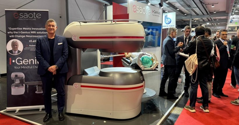 A man standing next to an MRI scanner at a medical expo