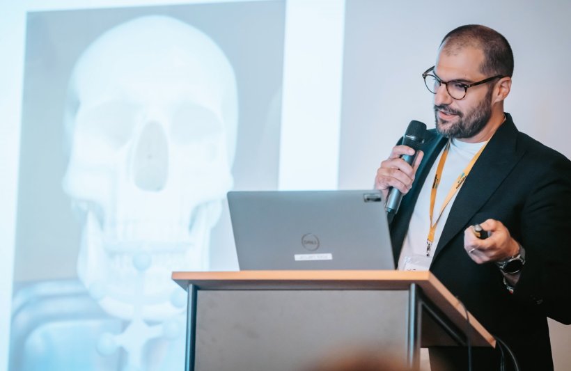 A man holding a microphone, standing behind a podium at a medical expert...